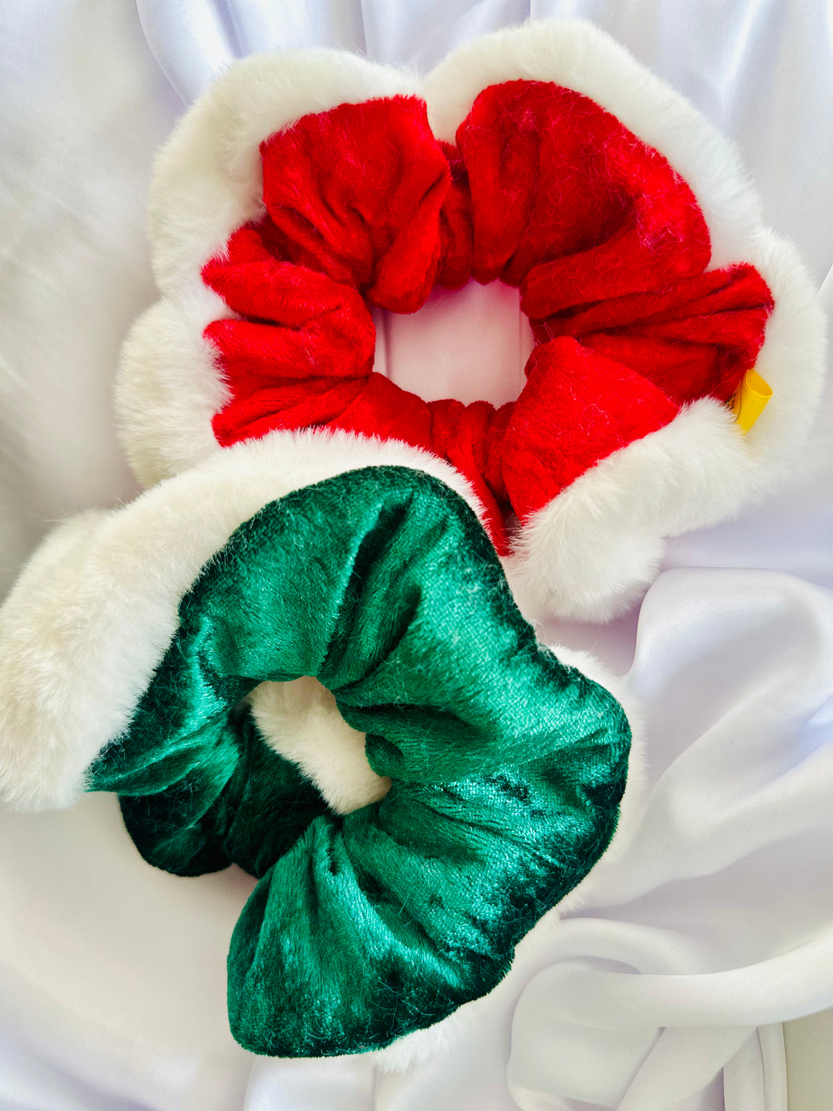 A green velvet Christmas scrunchie with white faux fur trim on a white surface.