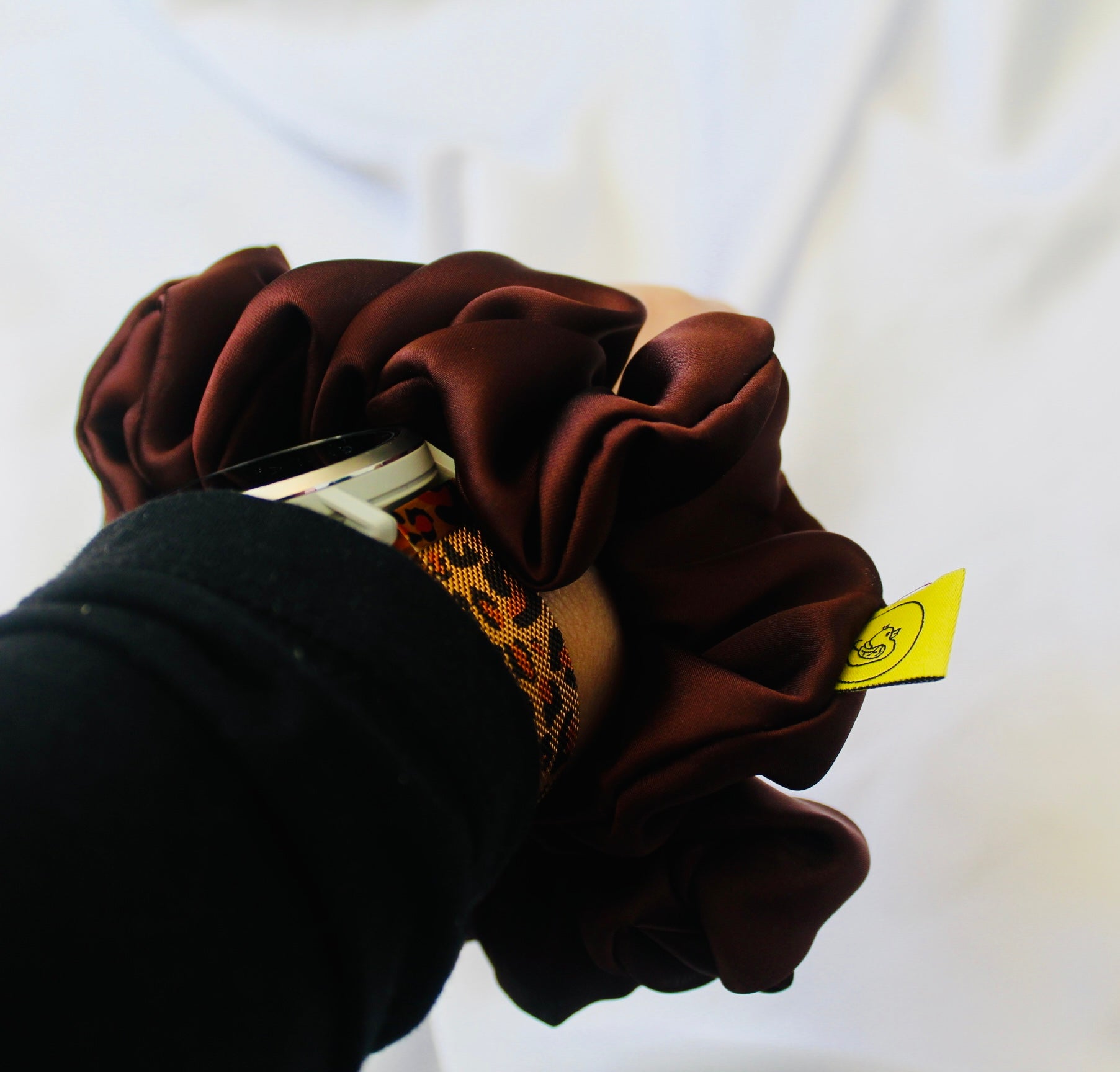 A satin scrunchie in a rich chocolate brown shade with a smooth and shiny texture and a ruched design.  This scrunchie is made from glossy satin giving it a soft, luxurious touch.  The deep chocolate brown colour is both bold and neutral, making it easy to style with a wide range of outfits.  The fabric is softly ruched over elastic, creating volume while remaining comfortable to wear.