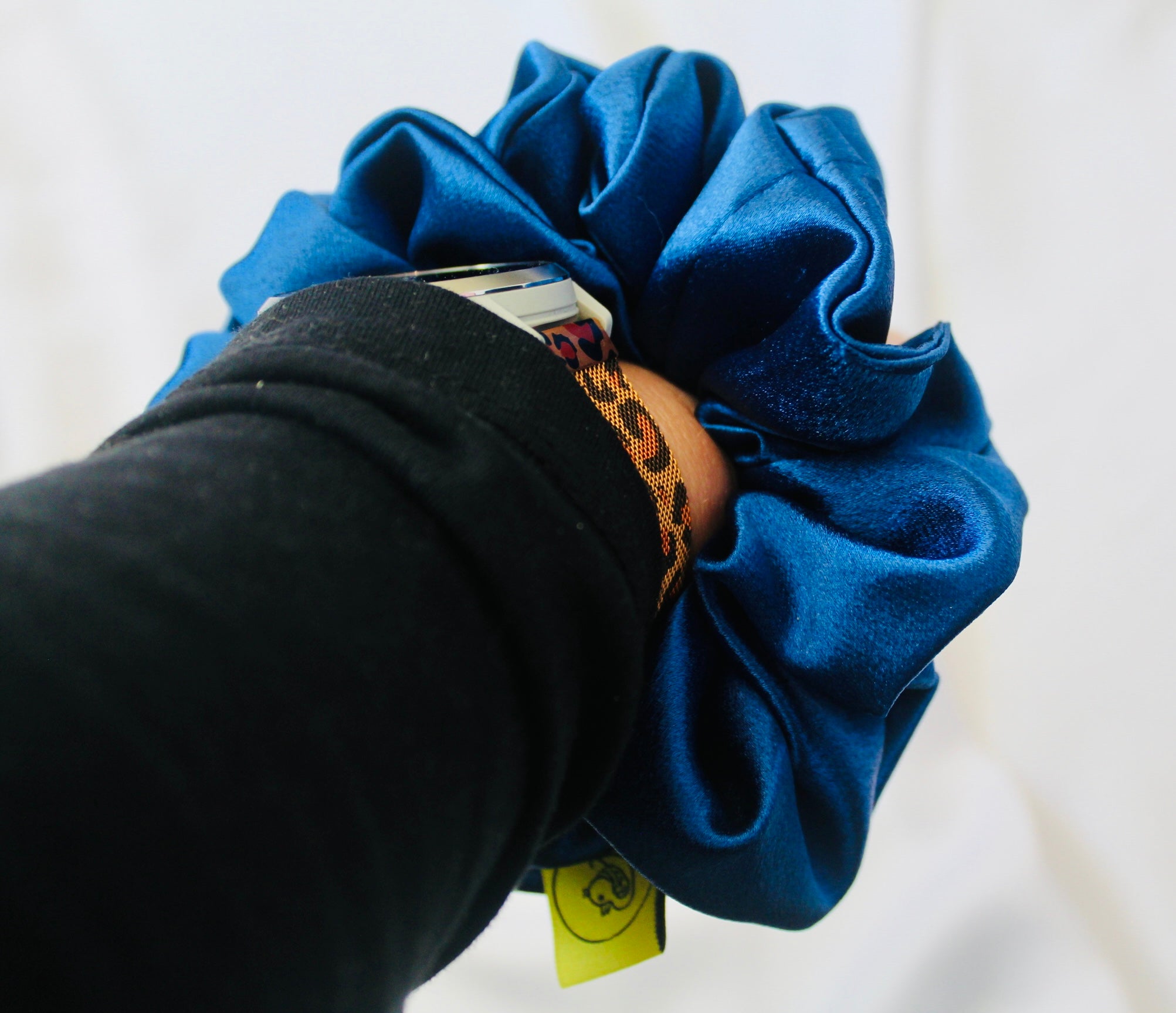 A satin scrunchie in a striking royal blue shade with a silky glossy texture and a ruched design.  Crafted from satin this scrunchie feels smooth and cool to the touch.  The bold royal blue colour stands out beautifully, making it a statement piece for both casual and evening looks.  The gathered satin fabric creates a full textured effect over the elastic ensuring a secure hold.