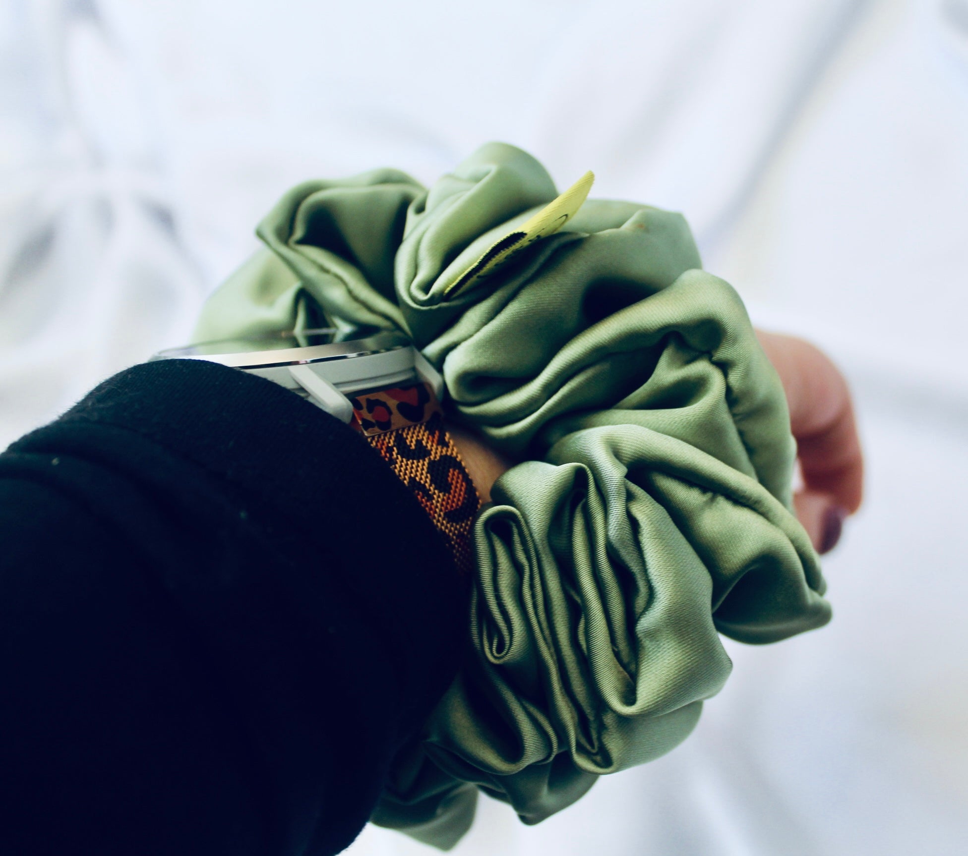 A satin scrunchie in a light green shade with a silky, glossy finish and a ruched design.  Crafted from smooth satin, this scrunchie feels soft and sleek against the hair.  The green tone has a timeless, earthy quality, perfect for both everyday wear and festive styling.  Its ruched fabric is stretched over an elastic band, providing a secure yet comfortable fit.