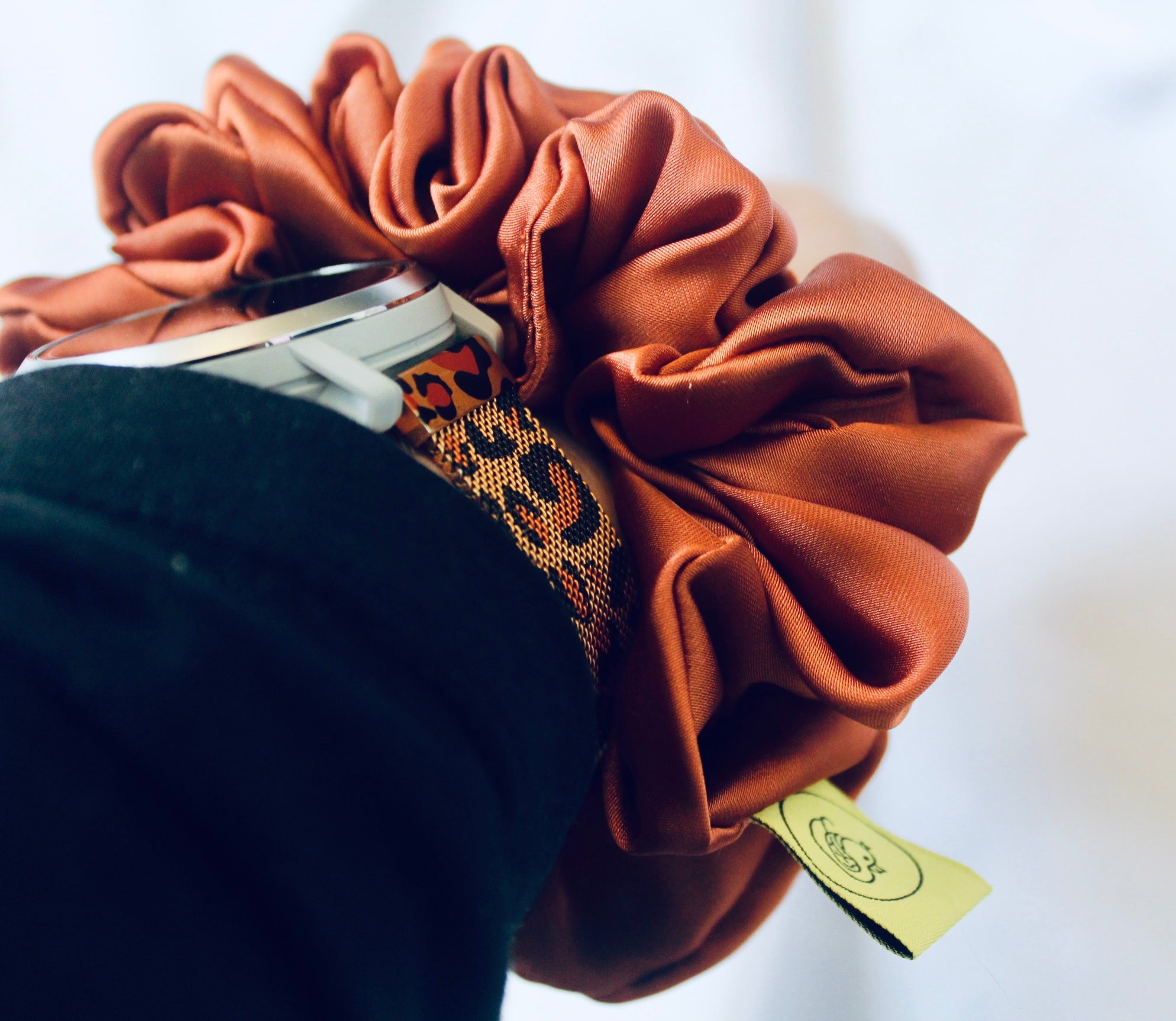 A satin scrunchie in a warm burnt orange shade with a smooth glossy texture and a ruched design.  This scrunchie is made from satin giving it a silky and lightweight feel.  The rich burnt orange colour captures the warmth of autumn leaves, making it perfect seasonal accessory.  The gathered fabric sits on an elastic core, creating a full ruffled look while keeping your hairstyle secure and comfortable.