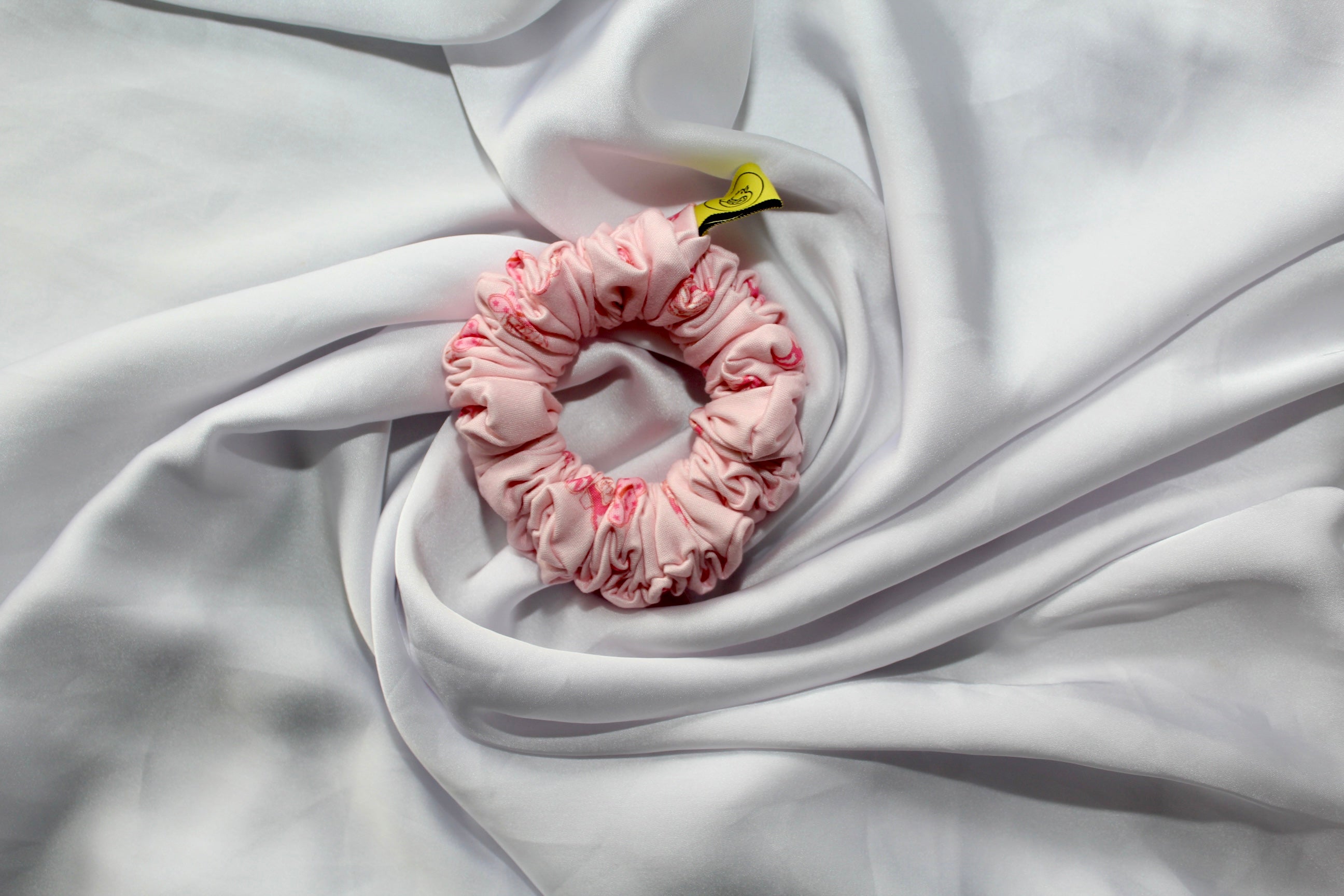 Pink hair scrunchie with cowgirl boots and hats on a white fabric background
